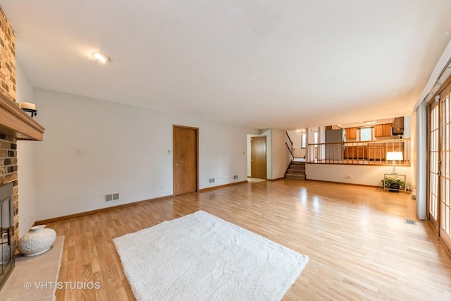 unfurnished living room with a fireplace, light hardwood / wood-style flooring, and plenty of natural light