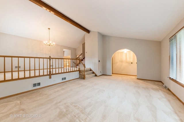 spare room with lofted ceiling with beams, light colored carpet, a wealth of natural light, and an inviting chandelier