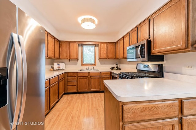 kitchen featuring sink, kitchen peninsula, stainless steel appliances, and light hardwood / wood-style flooring