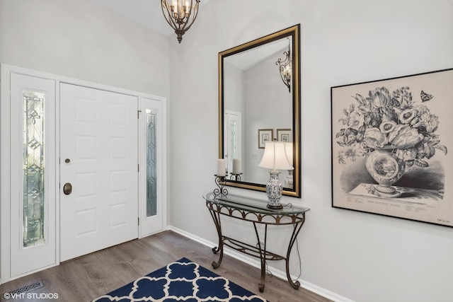 foyer entrance featuring a notable chandelier, a healthy amount of sunlight, and dark hardwood / wood-style flooring