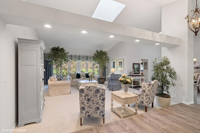 living room featuring a skylight, high vaulted ceiling, a chandelier, and light hardwood / wood-style floors