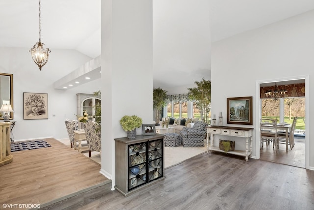 foyer entrance featuring hardwood / wood-style floors, an inviting chandelier, and high vaulted ceiling