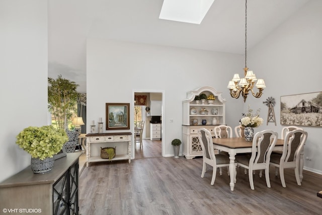 dining area with hardwood / wood-style floors, high vaulted ceiling, and a skylight