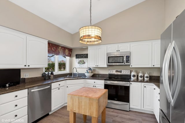 kitchen featuring pendant lighting, white cabinets, sink, dark hardwood / wood-style floors, and appliances with stainless steel finishes