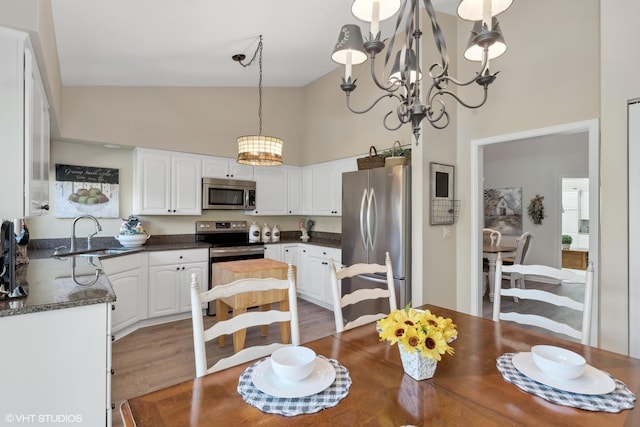 dining area featuring a chandelier, hardwood / wood-style floors, high vaulted ceiling, and sink