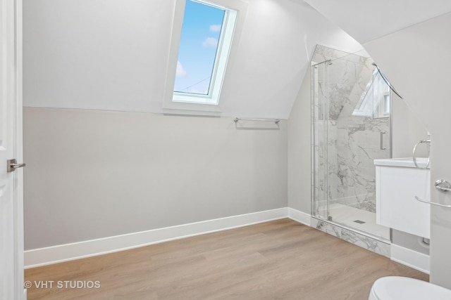 bathroom featuring hardwood / wood-style flooring, toilet, vaulted ceiling with skylight, and walk in shower