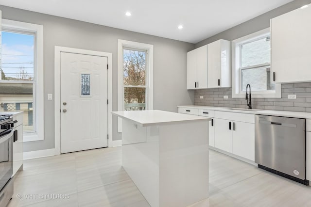 kitchen with a kitchen island, white cabinetry, sink, backsplash, and stainless steel dishwasher