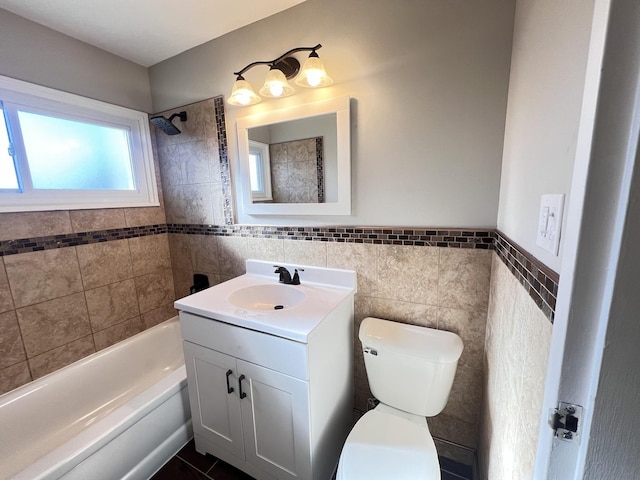 full bathroom featuring vanity, tiled shower / bath, tile patterned flooring, toilet, and tile walls