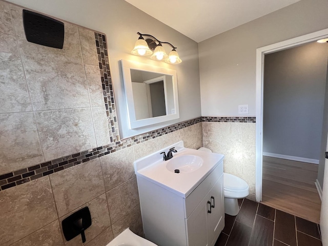 bathroom with vanity, toilet, and tile walls