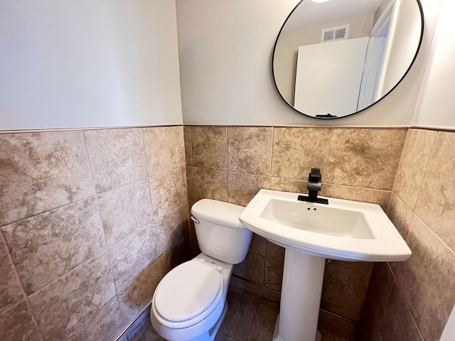 bathroom featuring toilet and tile walls