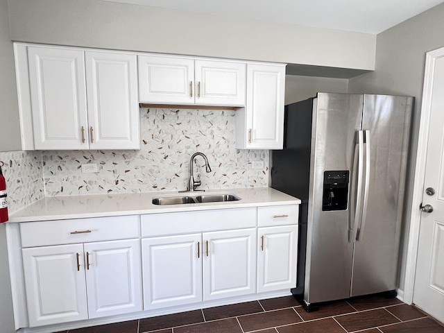 kitchen with decorative backsplash, stainless steel fridge, white cabinetry, and sink