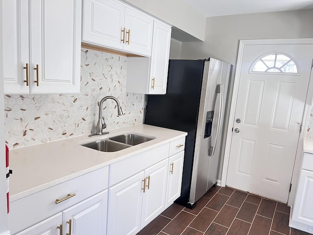 kitchen featuring tasteful backsplash, stainless steel fridge, white cabinetry, and sink