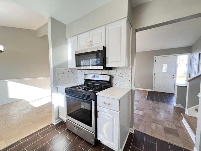 kitchen with white cabinetry, stainless steel appliances, and vaulted ceiling