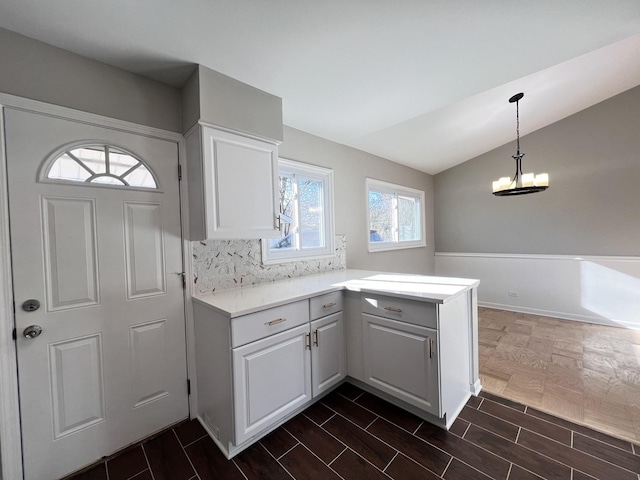 kitchen featuring white cabinetry, backsplash, kitchen peninsula, pendant lighting, and lofted ceiling