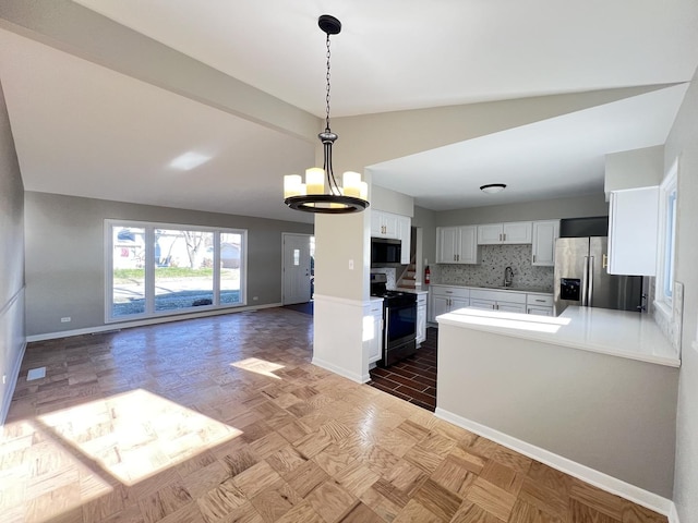 kitchen featuring backsplash, stainless steel appliances, vaulted ceiling, a notable chandelier, and white cabinetry