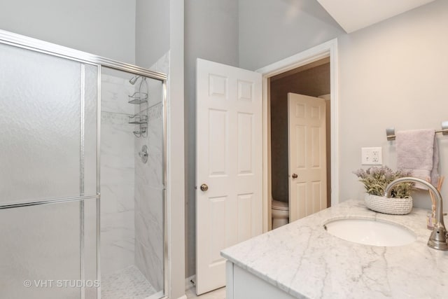 bathroom with an enclosed shower, vanity, and toilet