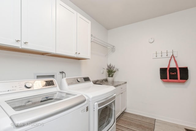 clothes washing area featuring cabinets and washer and dryer