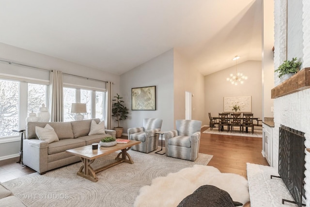 living room featuring vaulted ceiling, an inviting chandelier, light hardwood / wood-style floors, and a wealth of natural light