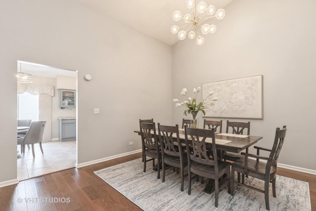 dining space with high vaulted ceiling, dark hardwood / wood-style floors, and a chandelier