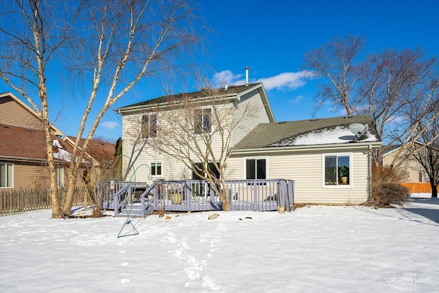 snow covered back of property with a deck