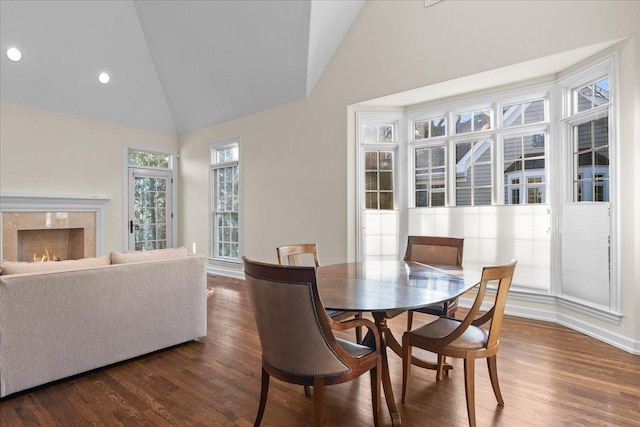 dining room with dark wood-type flooring, a high end fireplace, and high vaulted ceiling