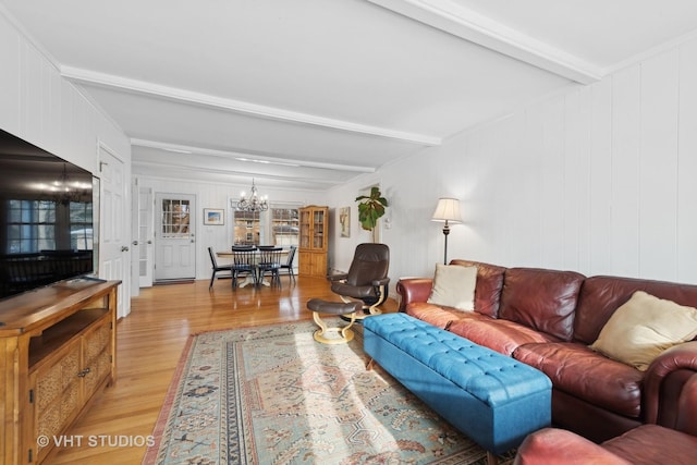 living room with light hardwood / wood-style flooring, beamed ceiling, and an inviting chandelier