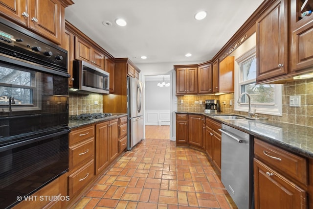 kitchen with backsplash, dark stone countertops, sink, and stainless steel appliances