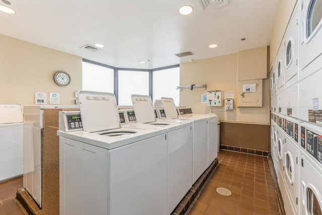 laundry room featuring dark tile patterned flooring, washer and clothes dryer, and stacked washer / dryer