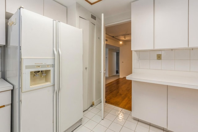 kitchen featuring backsplash, white fridge with ice dispenser, white cabinets, and light tile patterned floors