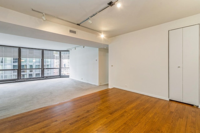 spare room with hardwood / wood-style floors, track lighting, and a wall of windows