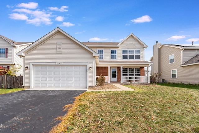 front of property with covered porch, a garage, and a front yard