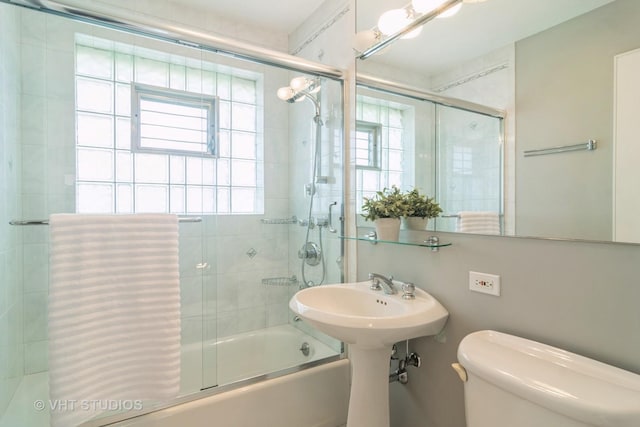 bathroom featuring a wealth of natural light, enclosed tub / shower combo, and toilet