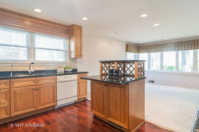 kitchen featuring a center island, dishwasher, sink, dark hardwood / wood-style flooring, and dark stone countertops