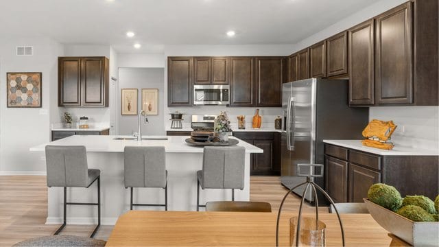 kitchen with dark brown cabinets, stainless steel appliances, sink, a breakfast bar area, and an island with sink