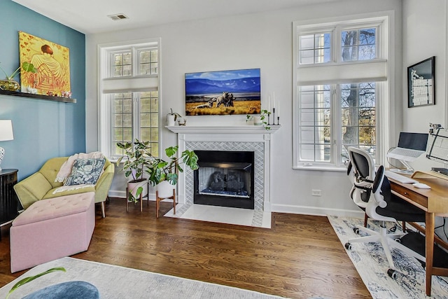 office area featuring a tiled fireplace and dark hardwood / wood-style flooring