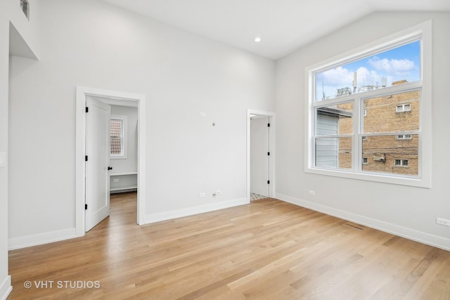 spare room with light hardwood / wood-style flooring and lofted ceiling