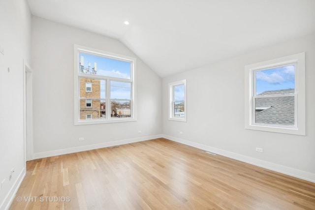 empty room with vaulted ceiling and light hardwood / wood-style floors