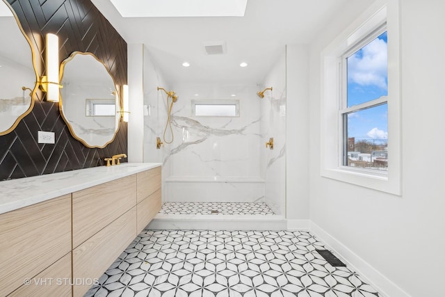 bathroom with a tile shower and vanity