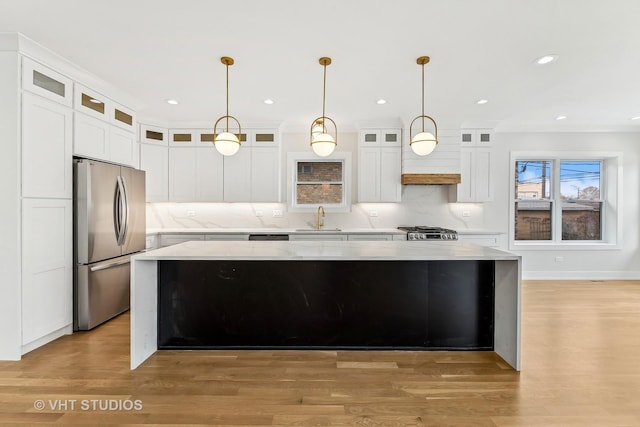 kitchen featuring white cabinets, light wood-type flooring, range, stainless steel fridge, and a kitchen island