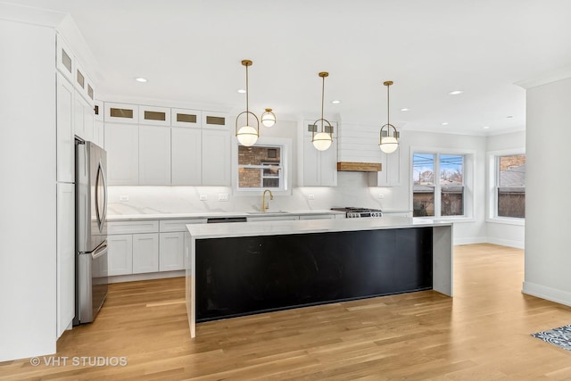 kitchen featuring a kitchen island, white cabinets, stainless steel refrigerator, and pendant lighting