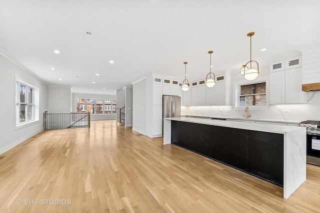 kitchen featuring stainless steel appliances, a center island, hanging light fixtures, and white cabinetry