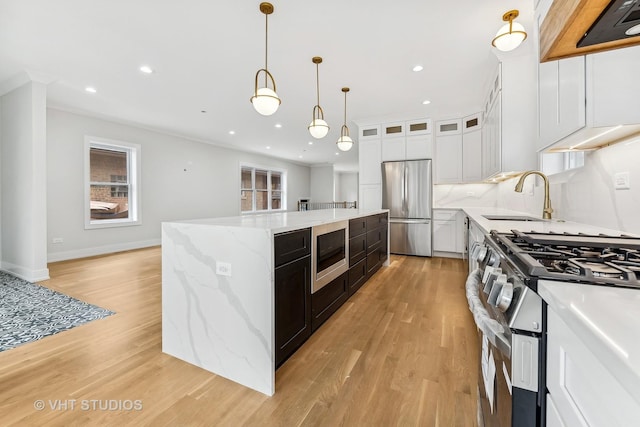 kitchen with sink, white cabinets, decorative light fixtures, a kitchen island, and appliances with stainless steel finishes