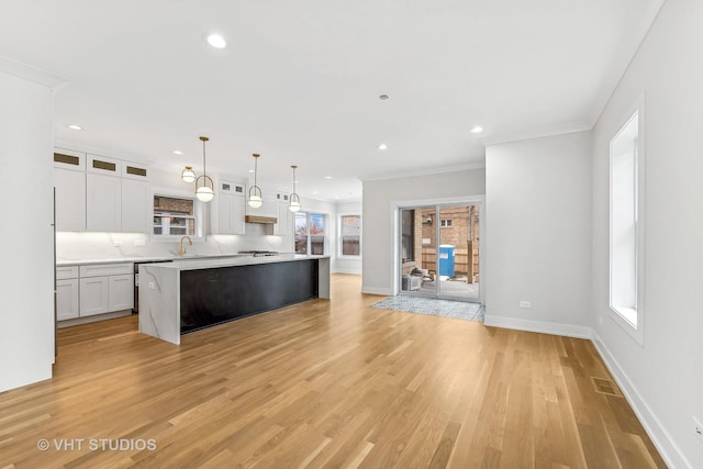 kitchen with decorative light fixtures, a center island, white cabinets, light hardwood / wood-style floors, and backsplash