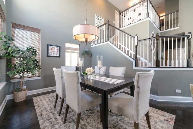 dining space featuring dark hardwood / wood-style flooring and a high ceiling