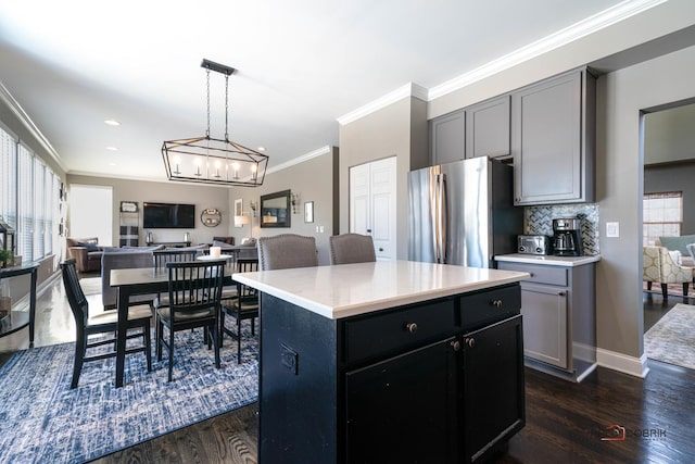 kitchen featuring crown molding, a center island, stainless steel refrigerator, dark hardwood / wood-style flooring, and backsplash