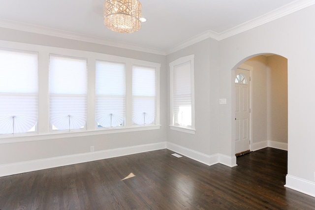 empty room with dark hardwood / wood-style floors, crown molding, and a chandelier