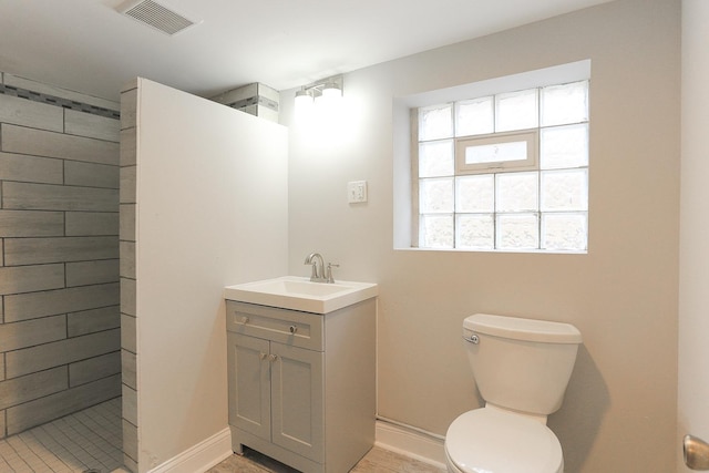 bathroom with tiled shower, vanity, and toilet