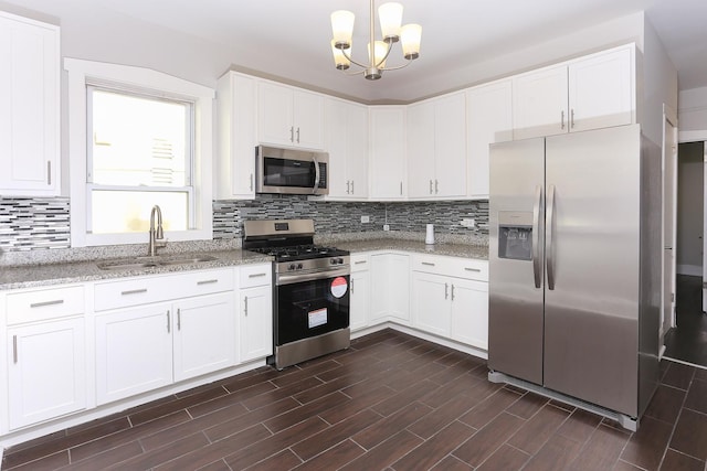 kitchen featuring light stone counters, stainless steel appliances, sink, pendant lighting, and white cabinetry