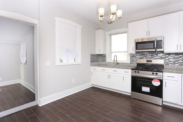 kitchen with decorative light fixtures, light stone counters, white cabinetry, and stainless steel appliances