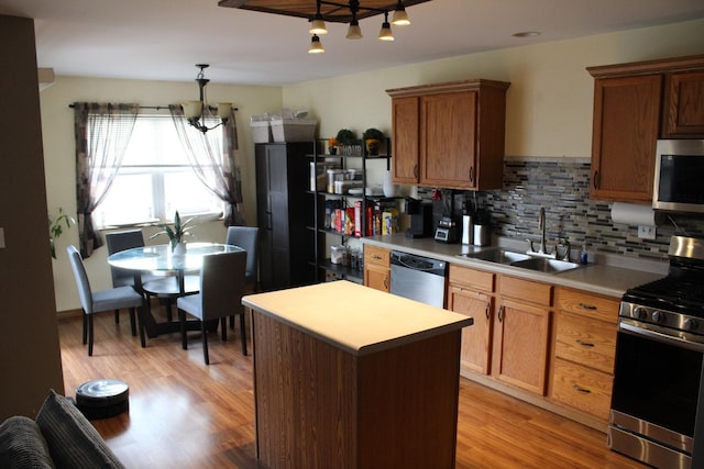 kitchen featuring sink, decorative backsplash, decorative light fixtures, light hardwood / wood-style floors, and stainless steel appliances